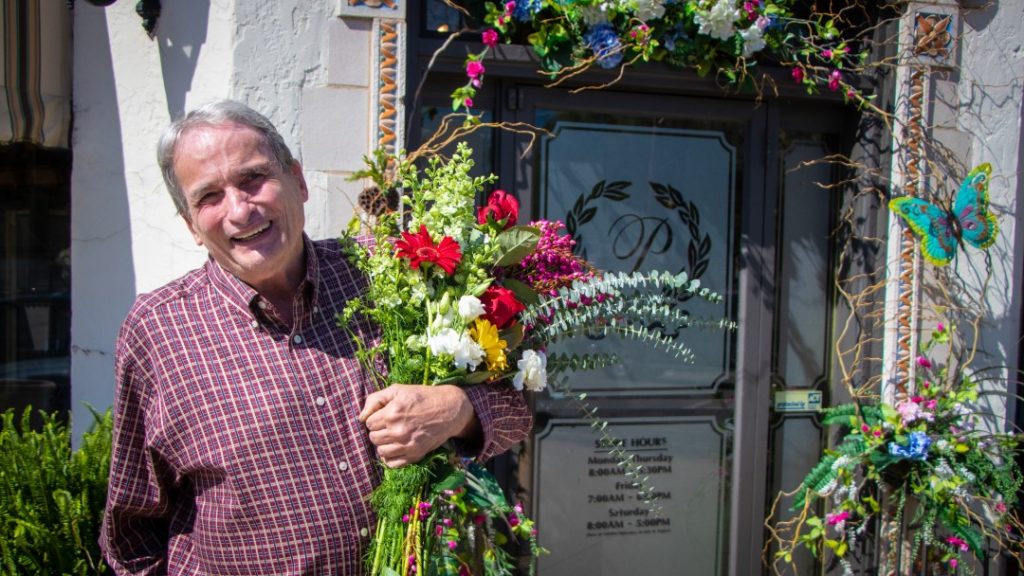 David Porterfield standing outside of Porterfields Inc with flowers