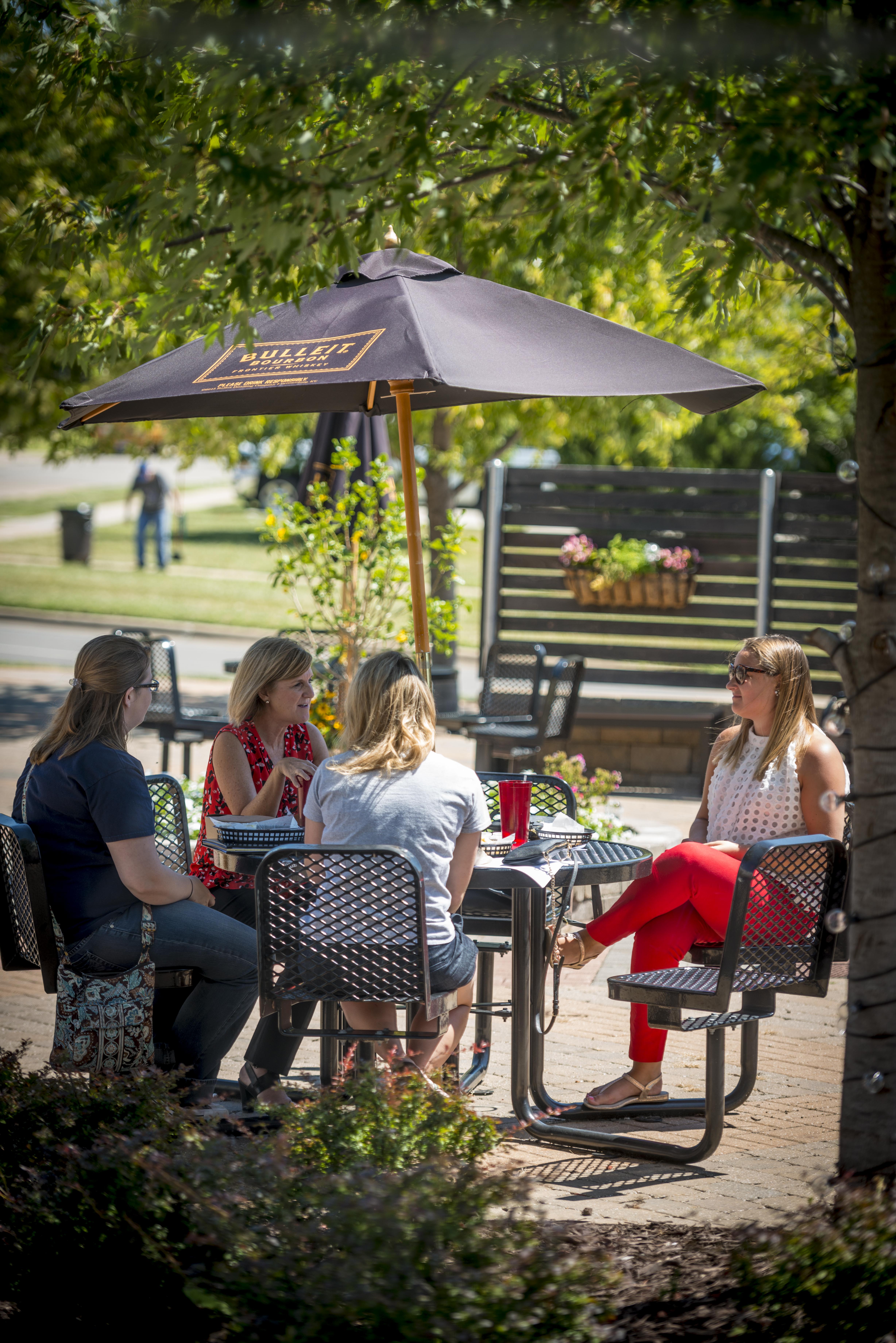 women sitting outside while discussing funding and eating at the Burgerstand Restaurant